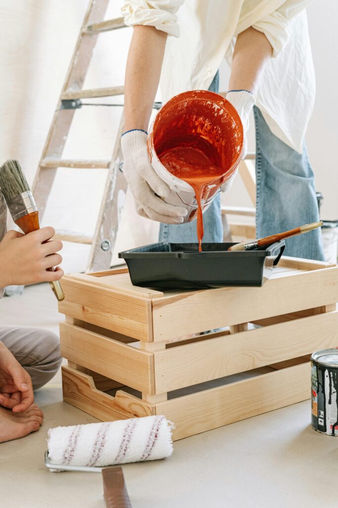 Close-up of people preparing paint and tools for a home renovation project indoors.
